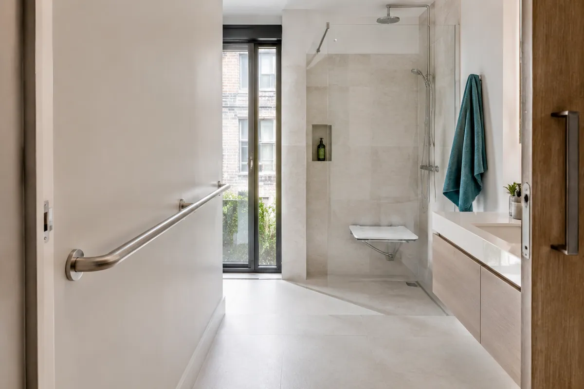 Main courante murale laissant un passage dégagé vers une douche senior de plain-pied